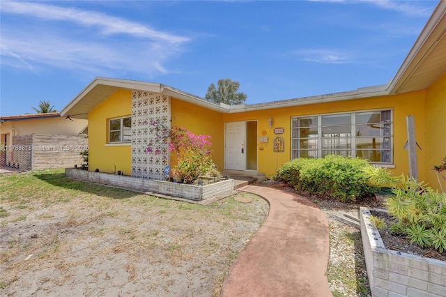 property entrance with stucco siding and fence