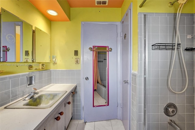 bathroom with tile patterned floors,  shower combination, tile walls, visible vents, and vanity