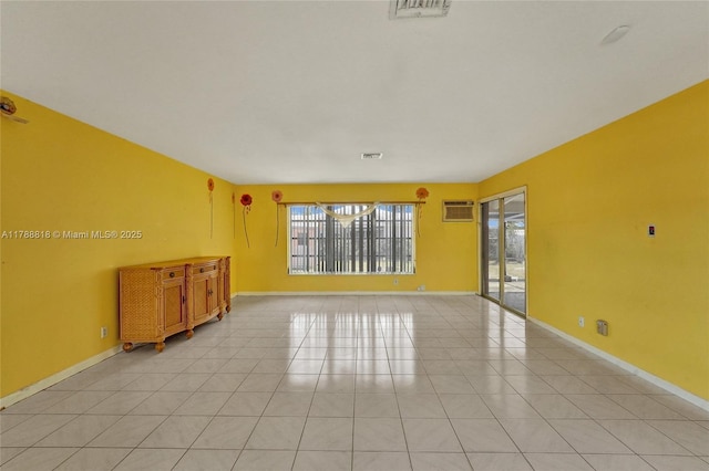 spare room featuring baseboards, visible vents, an AC wall unit, and light tile patterned floors