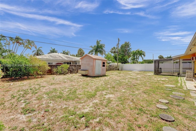 view of yard with a fenced backyard, an outdoor structure, and a storage unit