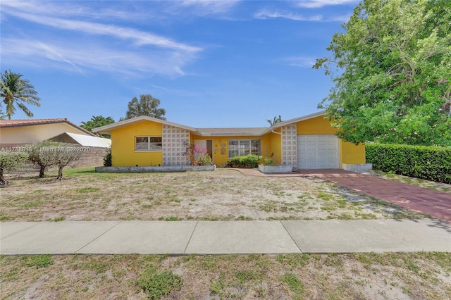 ranch-style house with a garage, driveway, stucco siding, and fence