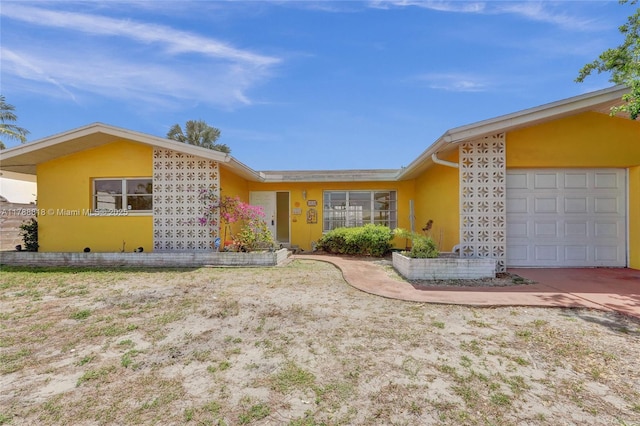 view of front facade with an attached garage, driveway, and stucco siding
