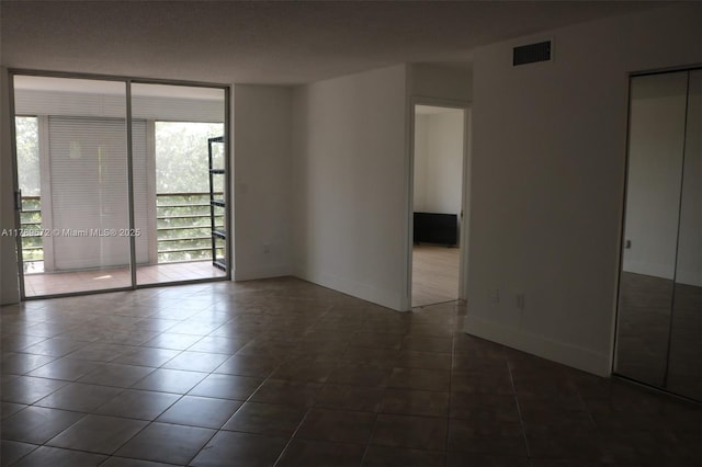 3490 Foxcroft Rd Unit B304, Miramar, FL 33025 - unfurnished room with a wall of windows, dark tile patterned floors, and baseboards