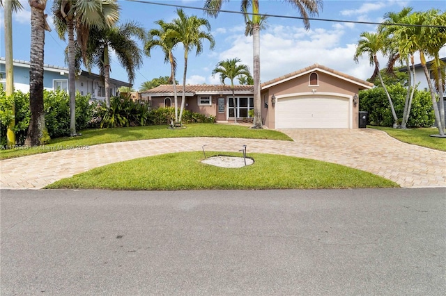 view of front of house with a tiled roof, a front yard, curved driveway, stucco siding, and a garage