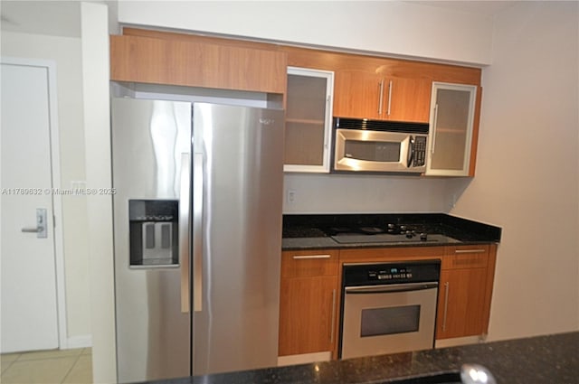 335 S Biscayne Blvd Unit 1904, Miami, FL 33131 - kitchen with stainless steel appliances, brown cabinetry, dark stone counters, and tile patterned floors
