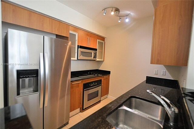 335 S Biscayne Blvd Unit 1904, Miami, FL 33131 - kitchen with stainless steel appliances, brown cabinetry, dark stone counters, and tile patterned floors
