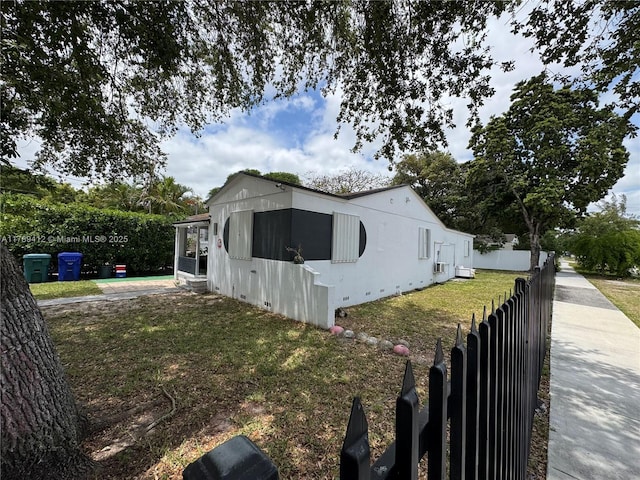 view of side of home with fence and a lawn