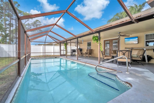 view of swimming pool with a ceiling fan, a patio area, french doors, and glass enclosure
