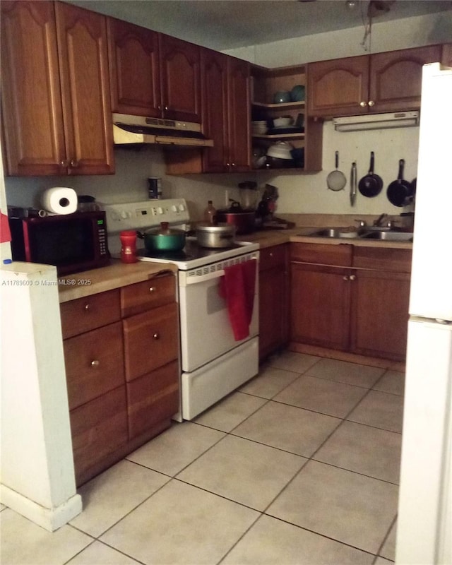 kitchen with under cabinet range hood, light countertops, a sink, light tile patterned floors, and white appliances
