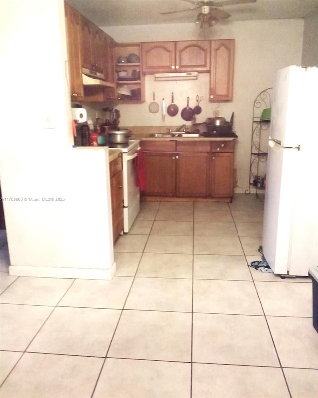 kitchen with a sink, a ceiling fan, white appliances, under cabinet range hood, and light tile patterned floors