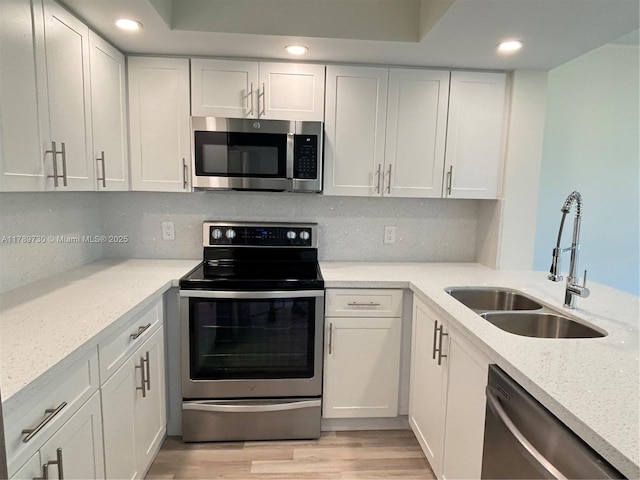 kitchen featuring recessed lighting, a sink, stainless steel appliances, tasteful backsplash, and white cabinetry