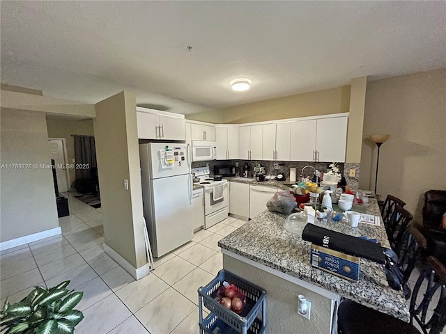 kitchen with backsplash, white cabinetry, white appliances, and light tile patterned floors