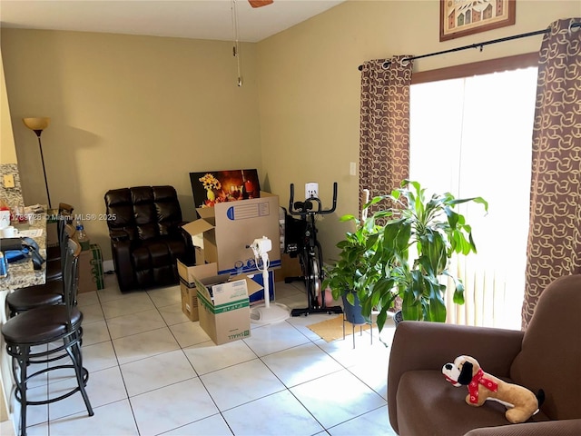 living area with light tile patterned flooring, plenty of natural light, and a ceiling fan