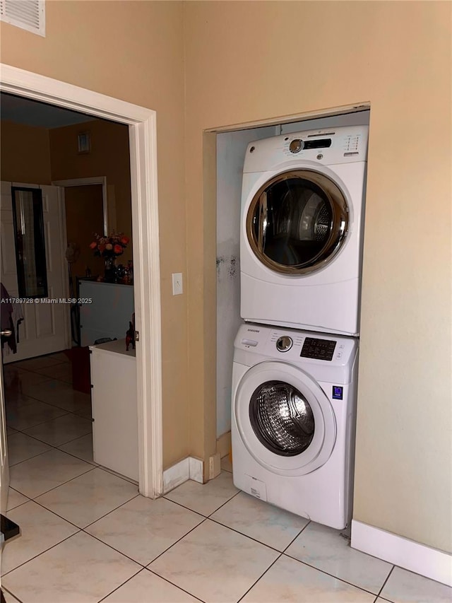 laundry area featuring baseboards, visible vents, stacked washer / dryer, and laundry area