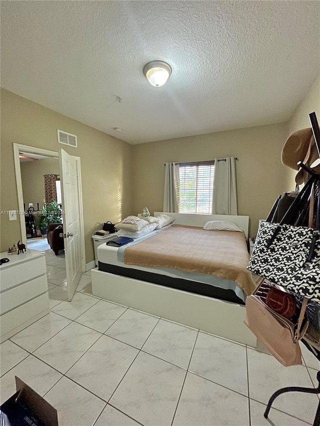 bedroom featuring visible vents, a textured ceiling, and light tile patterned floors