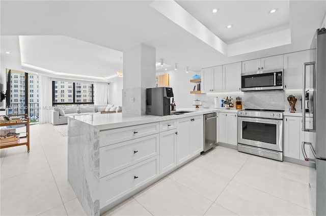 520 Brickell Key Dr Unit A713, Miami, FL 33131 - kitchen featuring stainless steel appliances, a tray ceiling, tasteful backsplash, white cabinets, and light tile patterned floors