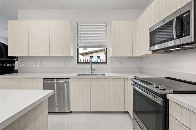 kitchen featuring modern cabinets, light brown cabinetry, stainless steel appliances, and a sink