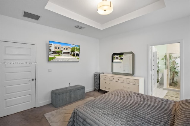 carpeted bedroom with baseboards, ensuite bath, visible vents, and a tray ceiling
