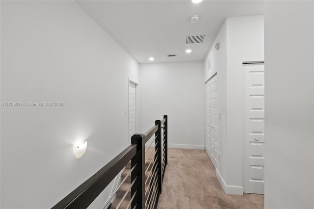 hallway featuring baseboards, light carpet, visible vents, and recessed lighting