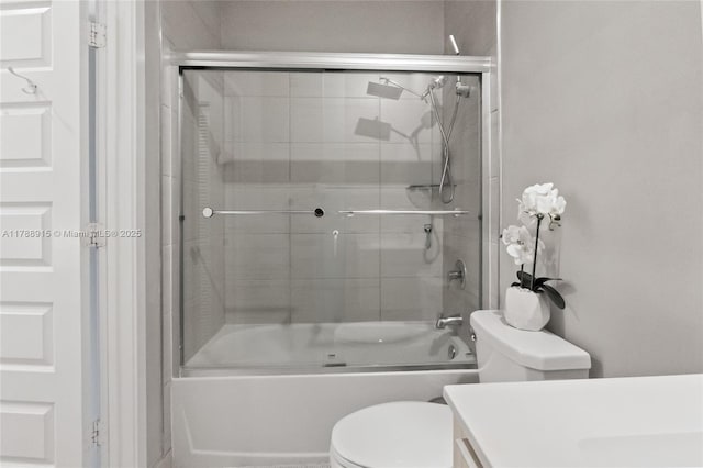 bathroom with vanity, enclosed tub / shower combo, and toilet