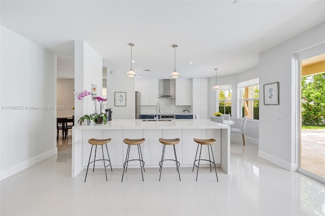 kitchen with wall chimney range hood, a sink, a breakfast bar, modern cabinets, and baseboards