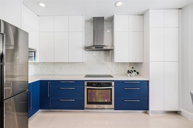 kitchen featuring modern cabinets, wall chimney range hood, stainless steel appliances, and blue cabinets