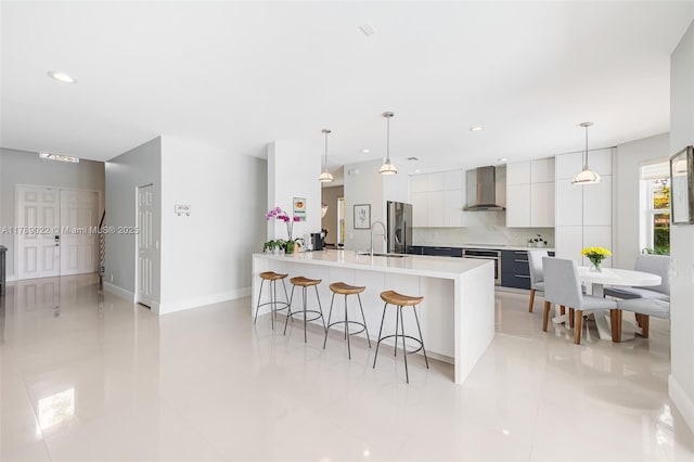 kitchen featuring white cabinets, stainless steel appliances, a kitchen breakfast bar, modern cabinets, and wall chimney range hood