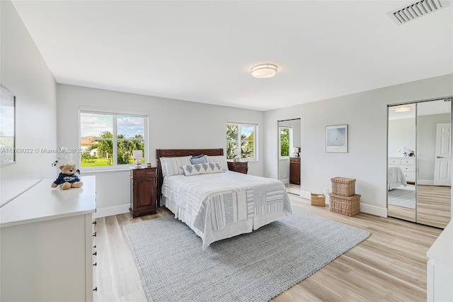 bedroom featuring light wood finished floors, baseboards, visible vents, and multiple windows