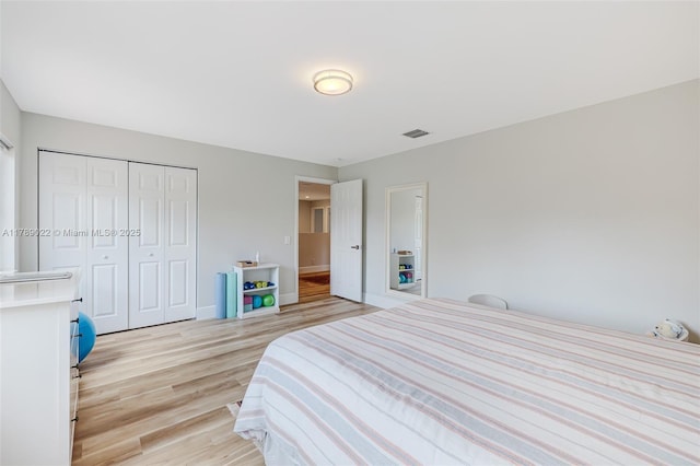 bedroom with a closet, visible vents, light wood finished floors, and baseboards