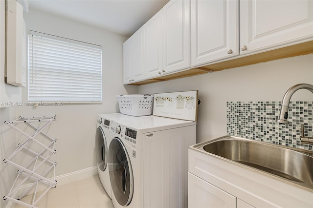 clothes washing area featuring washing machine and clothes dryer, cabinet space, a sink, and baseboards