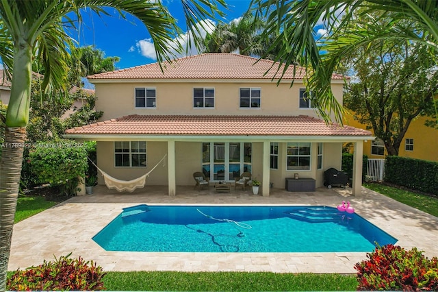 back of property with stucco siding, a tiled roof, fence, and a patio