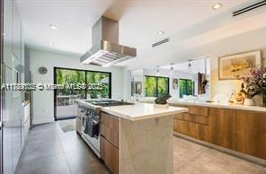 kitchen featuring modern cabinets, wall chimney range hood, brown cabinets, and stainless steel range