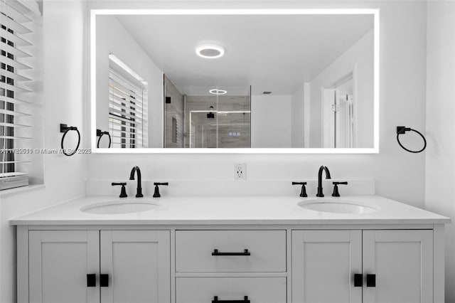 bathroom with double vanity, a stall shower, and a sink