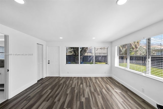empty room featuring recessed lighting, baseboards, and dark wood-style floors