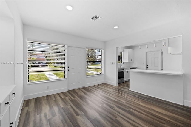 unfurnished living room with visible vents, baseboards, a sink, and dark wood-type flooring