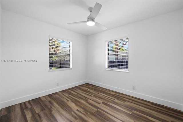 empty room with ceiling fan, a wealth of natural light, baseboards, and dark wood-style flooring