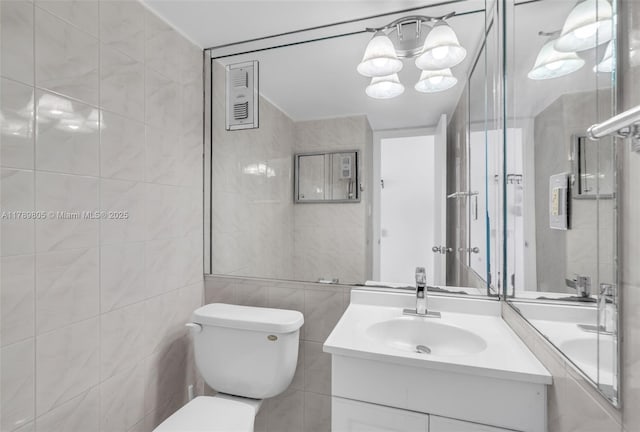 6900 Bay Dr Unit 11F, Miami Beach, FL 33141 - bathroom featuring toilet, an inviting chandelier, tile walls, and vanity