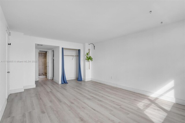 6900 Bay Dr Unit 11F, Miami Beach, FL 33141 - unfurnished bedroom featuring a closet, baseboards, and light wood-type flooring
