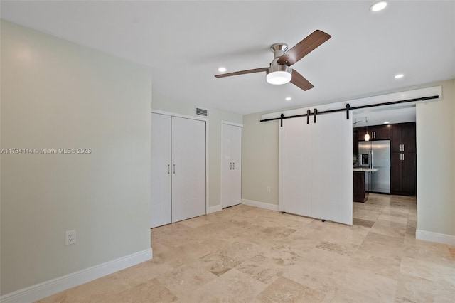 unfurnished bedroom with recessed lighting, two closets, stainless steel refrigerator with ice dispenser, and a barn door