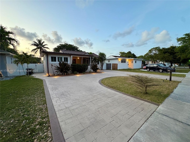 ranch-style house with fence, curved driveway, a front yard, and a tiled roof