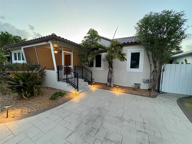 view of front of house with fence, stucco siding, a tiled roof, and a gate