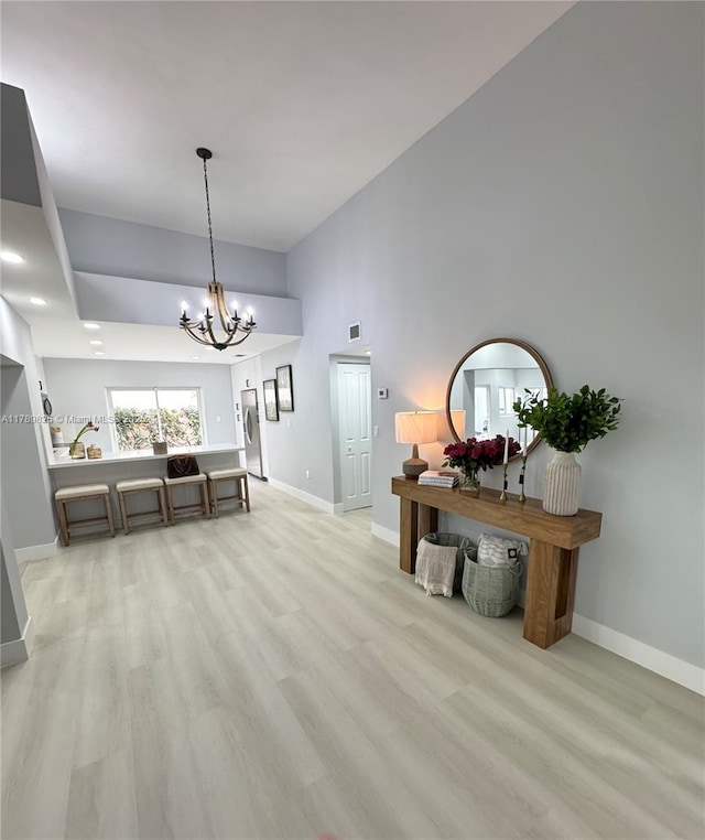 interior space with an inviting chandelier, light wood-style floors, visible vents, and baseboards