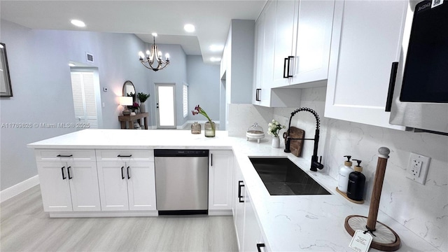 kitchen featuring a peninsula, appliances with stainless steel finishes, white cabinetry, and a sink
