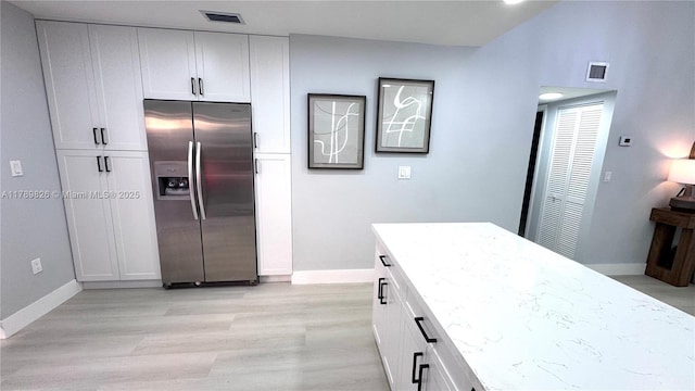 kitchen featuring visible vents, stainless steel refrigerator with ice dispenser, and baseboards