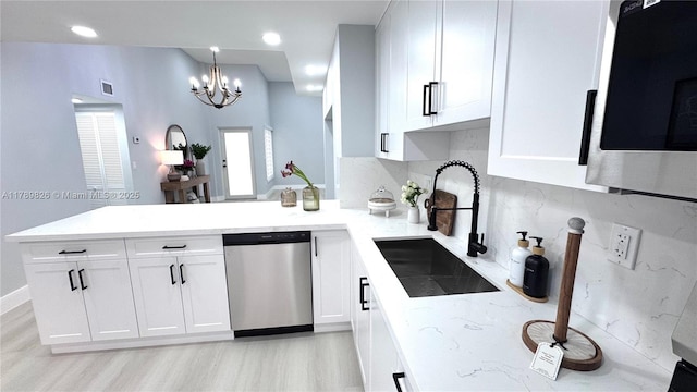 kitchen with a chandelier, white cabinets, stainless steel appliances, a sink, and a peninsula
