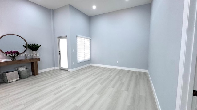foyer featuring baseboards, a towering ceiling, wood finished floors, and recessed lighting