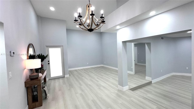 interior space with light wood-style floors, baseboards, an inviting chandelier, recessed lighting, and a high ceiling