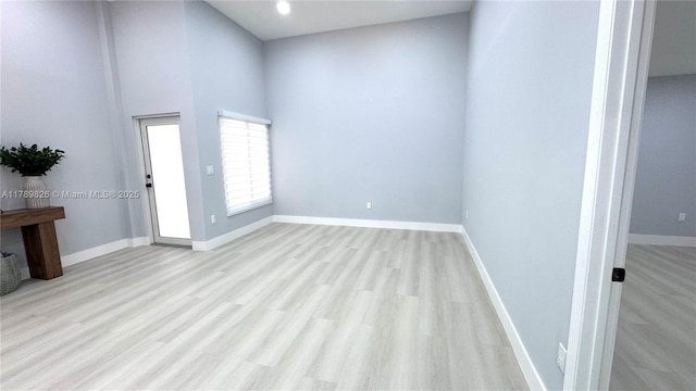 unfurnished room with baseboards, wood finished floors, and a high ceiling