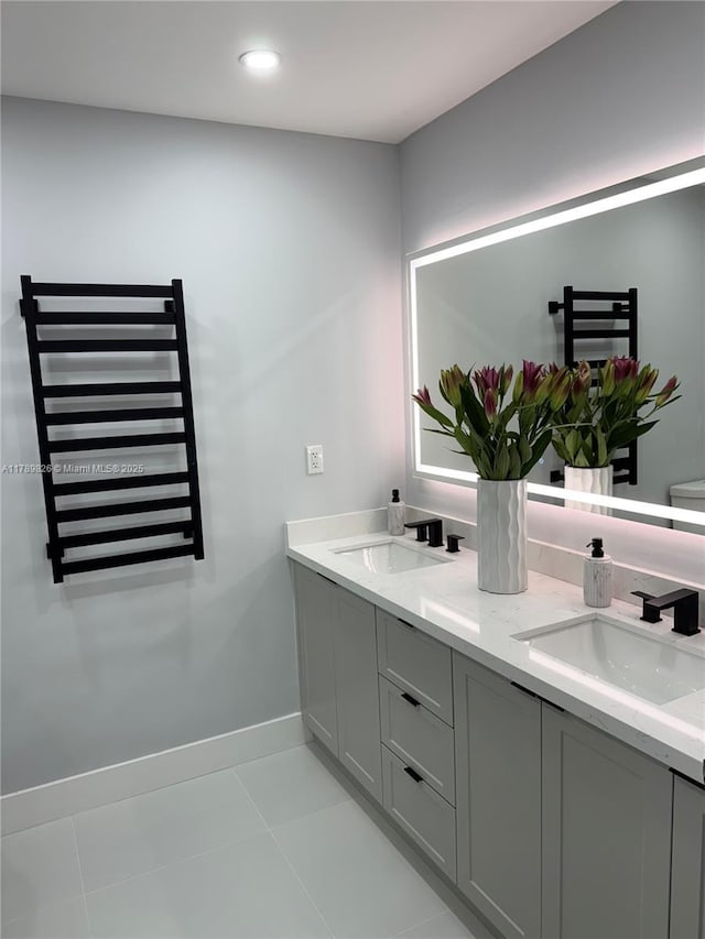bathroom featuring double vanity, tile patterned floors, baseboards, and a sink