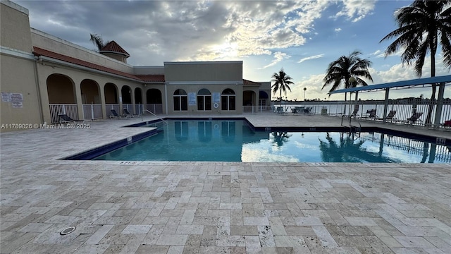 community pool with fence and a patio area
